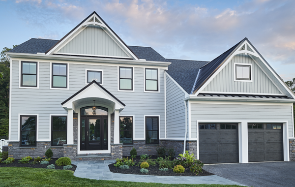 a large white house with Wolf building products and a black garage door