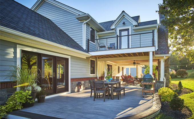 the back of a house with a large deck with a table and chairs on it