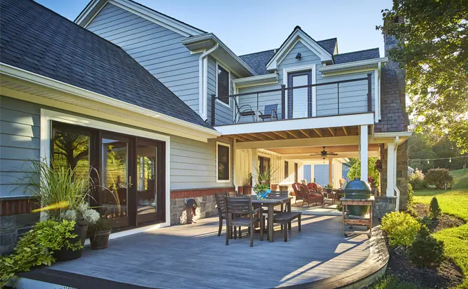 the back of a house with a large deck with a table and chairs on it